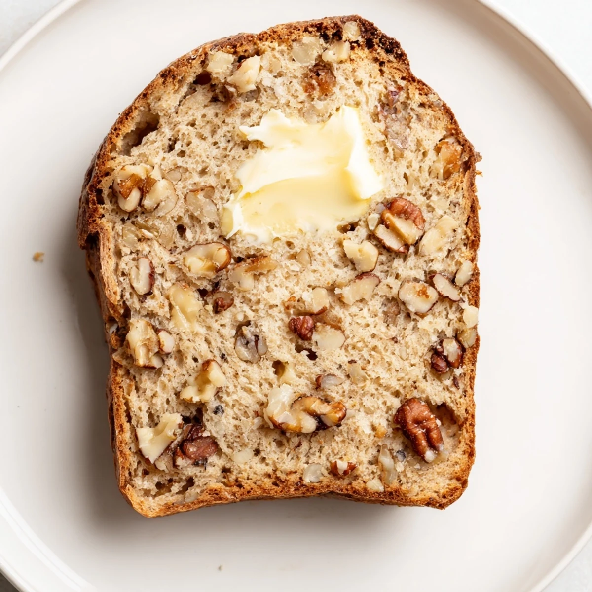 A close-up of a warm, just-baked Nutty Whole Wheat Loaf Bread, perfect for breakfast with butter.