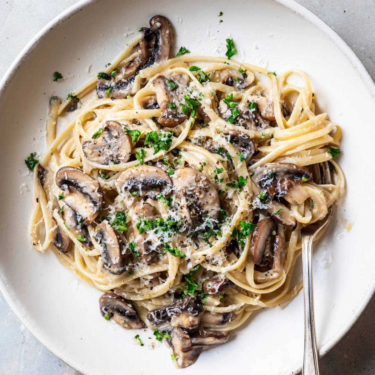 A comforting, elegant Creamy Mushroom Linguine served hot with fresh parsley and a sprinkle of shaved Parmesan.  