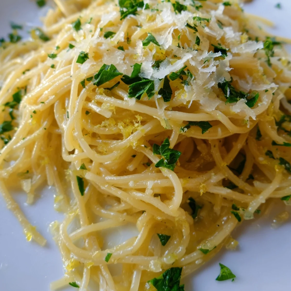 Steaming bowl of Lemon Butter Pasta Light garnished with chopped parsley and grated Parmesan, ready to serve.  