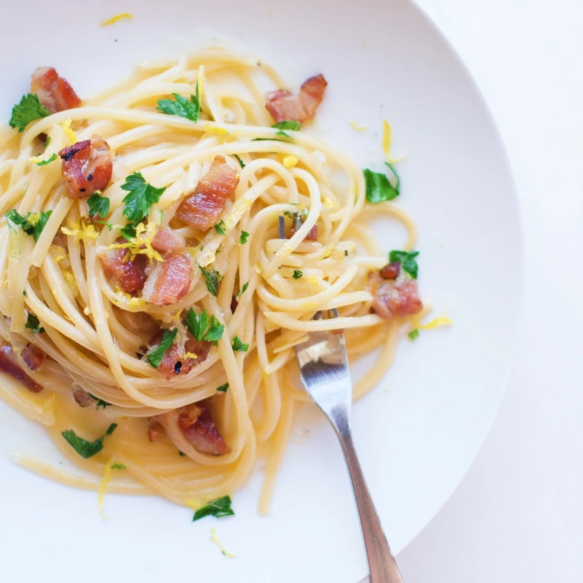 Family-style bowl of Crispy Bacon Linguine topped with extra Parmesan and a sprinkle of red pepper flakes.