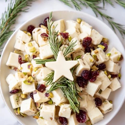 Festive Cranberry White Cheddar Tree appetizer with red cranberries, green herbs, cheese cubes.
