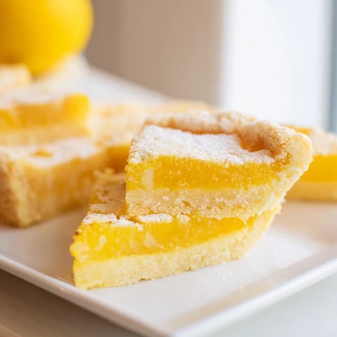 Golden, triangular lemon bars dusted with powdered sugar, a perfect easy dessert to savor.