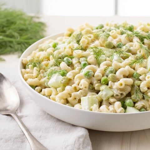 A vibrant bowl of Creamy Dill Pickle Pasta Salad featuring ditalini pasta, diced pickles, and sweet green peas coated in a zesty dressing.  