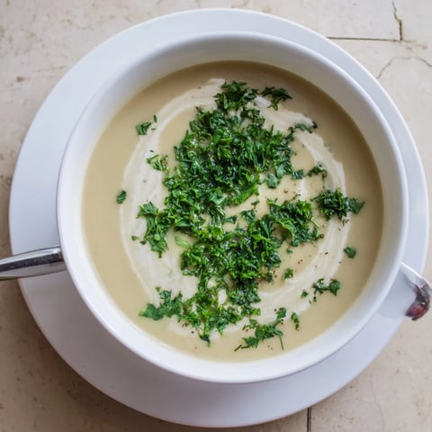Creamy roasted parsnip and herb soup in a rustic bowl, garnished with fresh dill and chives for a comforting winter meal.