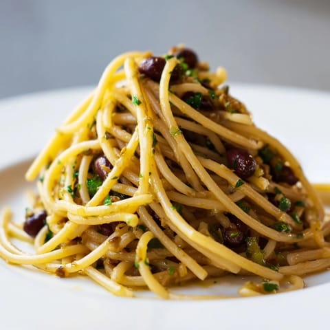 Bright Mediterranean flavors in a bowl of Olive Tapenade Pasta, garnished with parsley and vegan Parmesan for a dairy-free meal.
