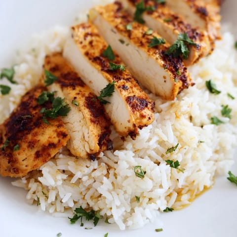 Steaming bowl of Garlic Butter Rice with Chicken, garnished with fresh parsley and lemon wedges, served alongside a colorful salad.