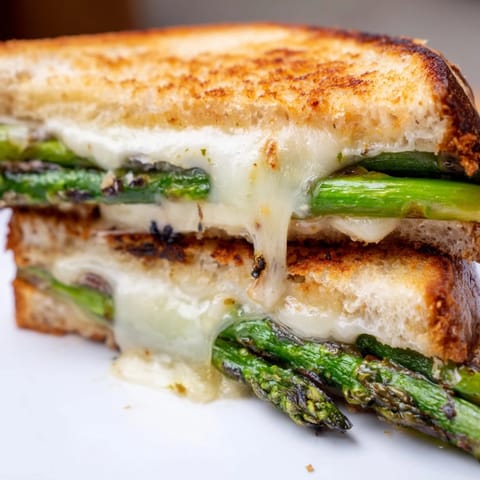 Freshly grilled asparagus and creamy Brie cheese fill this Asparagus & Brie Grilled Cheese, served warm beside a crisp green salad.