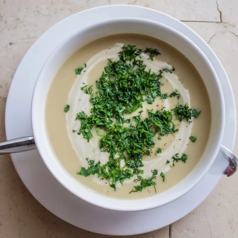 Creamy roasted parsnip and herb soup in a rustic bowl, garnished with fresh dill and chives for a comforting winter meal.
