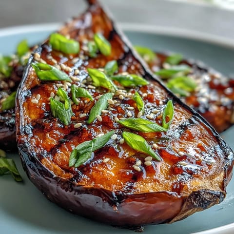 Roasted eggplant halves glistening with sweet miso glaze, caramelized and topped with sesame seeds and green onions.