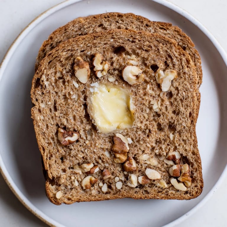 This freshly baked Nutty Whole Wheat Loaf Bread shows a rustic loaf with visible nuts throughout.