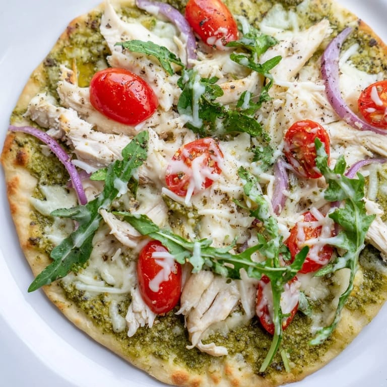 Warm pesto covers a flatbread with tender chicken and mozzarella; this easy Pesto Chicken Flatbread is delicious.