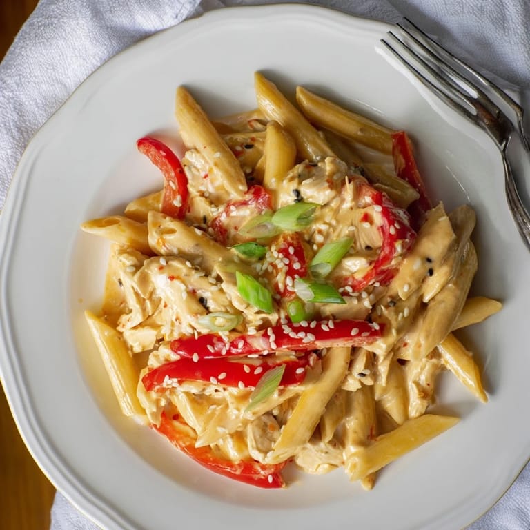 A vibrant plate of Sweet Chili Chicken Pasta featuring colorful red bell pepper strips and a glossy sauce.
