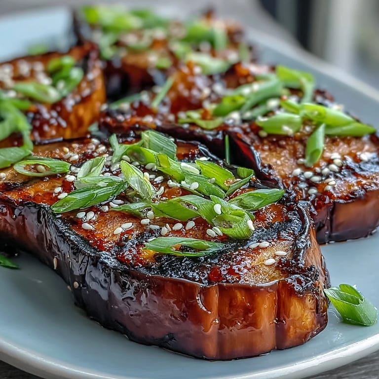 Soft roasted eggplant glazed with rich miso sauce, garnished with toasted sesame seeds and fresh green onion slices.
