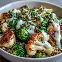 Golden-brown roasted broccoli, cauliflower, and Brussels sprouts are arranged over fluffy quinoa in a Roasted Brassica Bowl. 