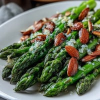 Vibrant asparagus spears glisten in lemon butter, topped with golden toasted almonds for a bright spring side dish.