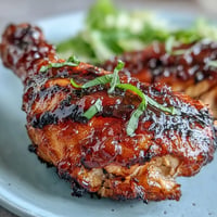 Juicy BBQ chicken drumsticks with spicy peach glaze, grilled for a sweet and tangy bite.